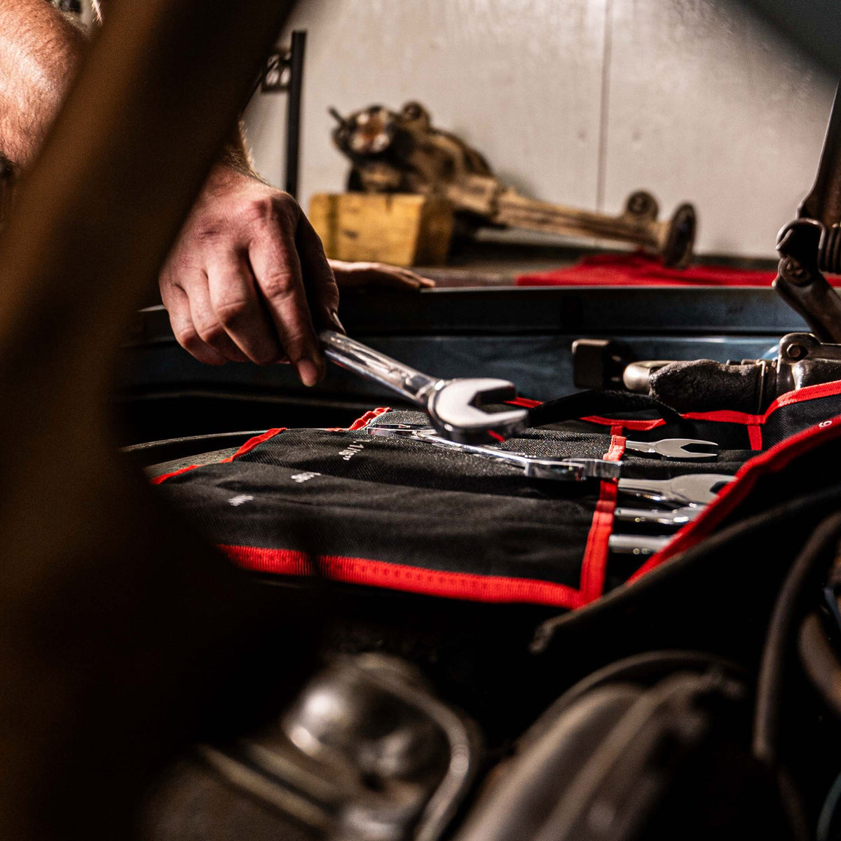 SUNEX Angle Head Wrenches resting on an engine under a car hood and being used by a technician.