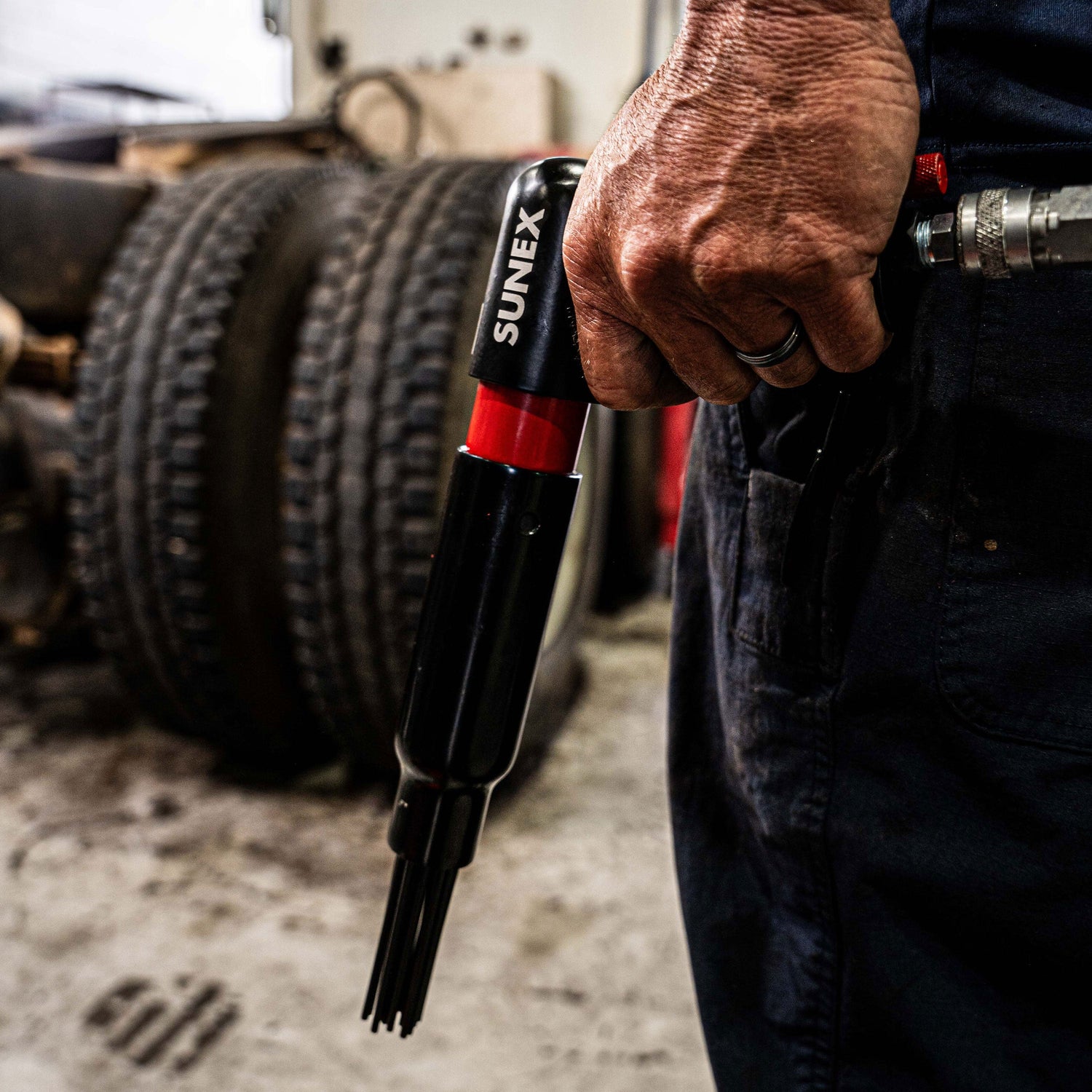 SX246 Pistol Grip Needle Scaler being held by a technician in a Diesel Maintenance environment