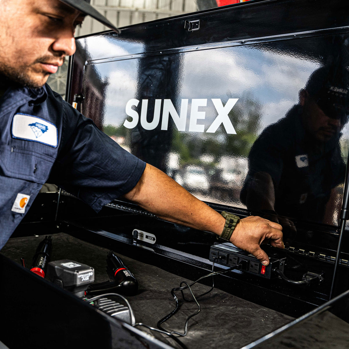 An automotive technician turning on the power of a SUNEX Tools Powered Service Cart