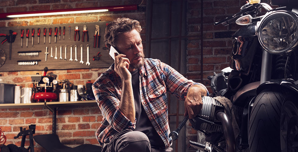 Mechanic on phone with Motorcycle and Tools in the background