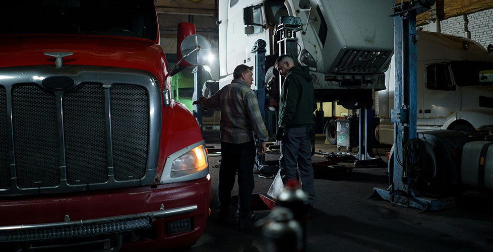 Two technicians having a conversation inside a diesel garage.